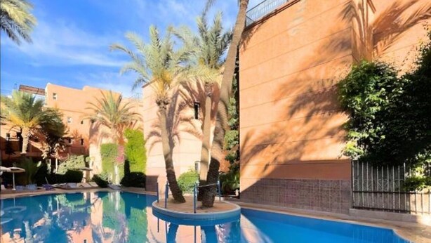 A swimming pool with palm trees and a building in the background.