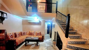 A spacious living area with a sofa set, a coffee table, and a staircase with decorative railings.