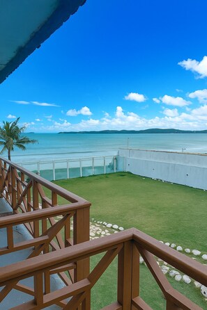 Un balcón con vista a un mar tranquilo y colinas lejanas.