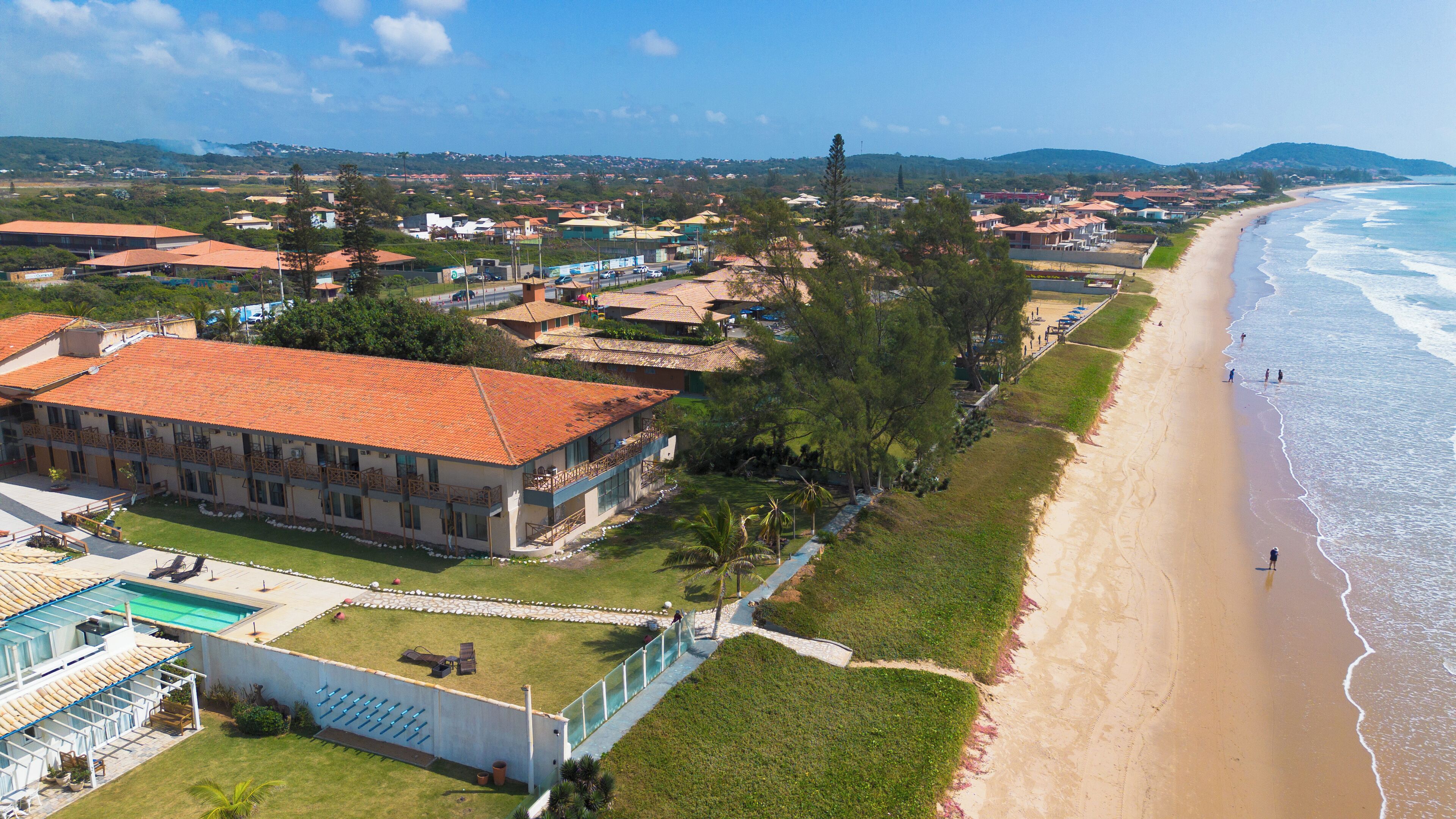 A coastal hotel with multiple buildings, a swimming pool, and a beach view.