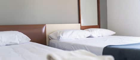 A hotel room with two beds, white linens, a wooden headboard, and a framed picture on the wall.