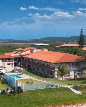 Un hotel con varias construcciones, una piscina y un césped cuidado.
