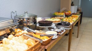 Un bufé con diversos alimentos, incluyendo pasteles, repostería y pan.