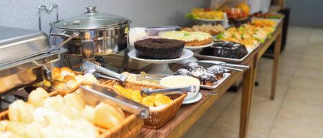 A buffet with various food items including cakes, pastries, and bread.