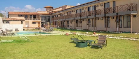 Een hotel met een zwembad, terras en een verzorgd gazon.