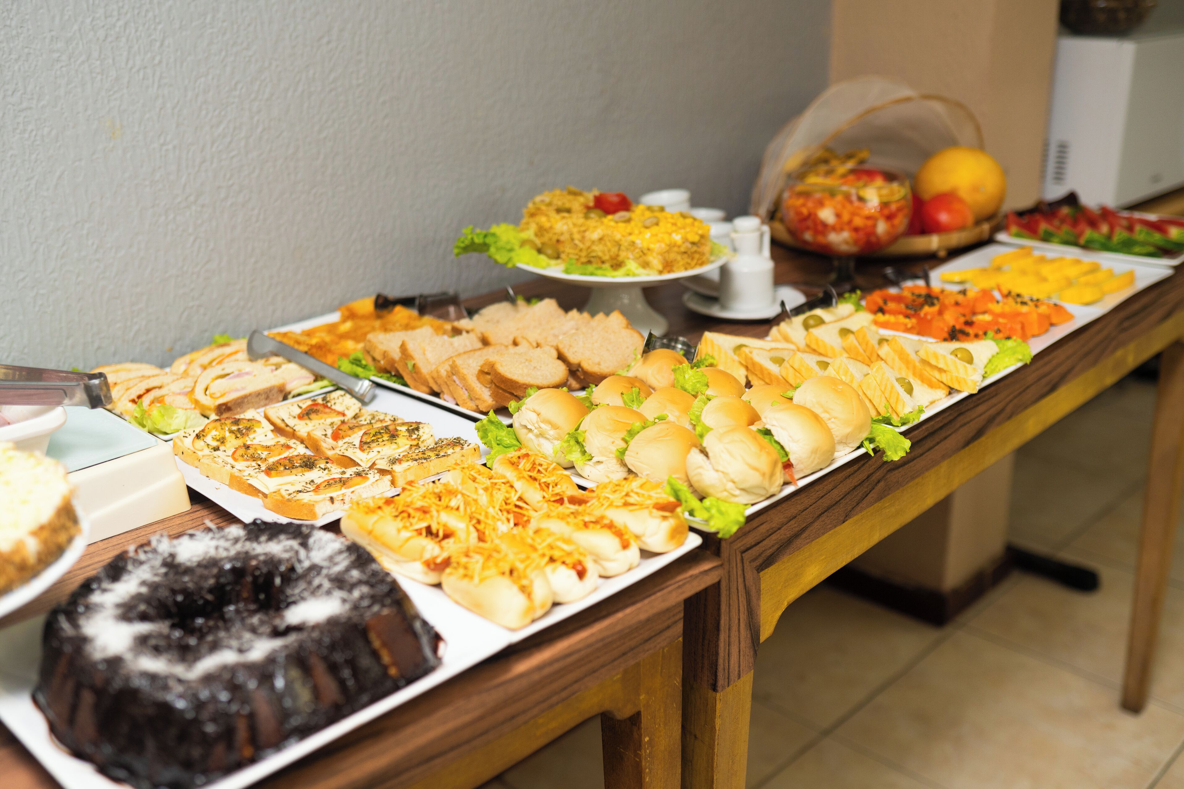A buffet table with various food items including sandwiches, salads, and a bundt cake.