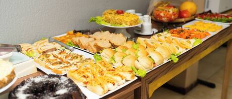 A buffet table with various food items including sandwiches, salads, and a bundt cake.