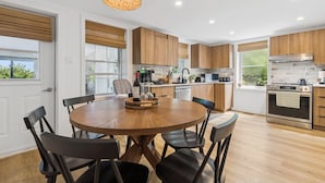 Uma cozinha moderna com armários de madeira, uma mesa de jantar redonda com cadeiras e um lustre.