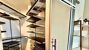 A compact kitchen with built-in shelves, a drying rack, and a small seating area.