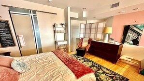 A bedroom with a bed, a desk, a chair, a wardrobe, and a mirror.
