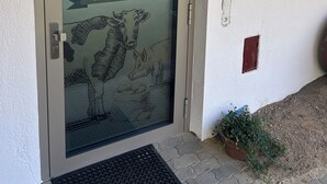 A door with a frosted glass panel featuring a cow and calf illustration, a metal handle, and a small potted plant beside it. - Wandlhof vacation apartment (Niederösterreich)
