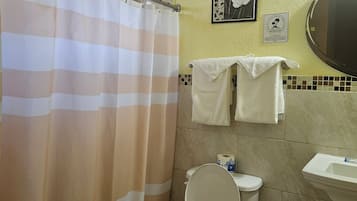 Un baño con cortina de ducha, dos toallas, un inodoro y un lavabo.