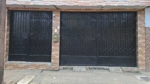 A building with two large black metal gates, a brick facade, and a number '530' on the wall. - PALO VERDE HOUSE  (Iquitos)