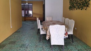 A dining area with a table set for four, a bench, and a decorative wall. - PALO VERDE HOUSE  (Iquitos)
