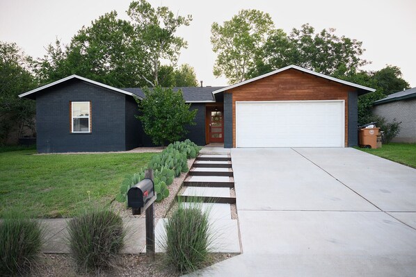 A modern two-story house with a garage, a front yard with a pathway, and a mailbox.