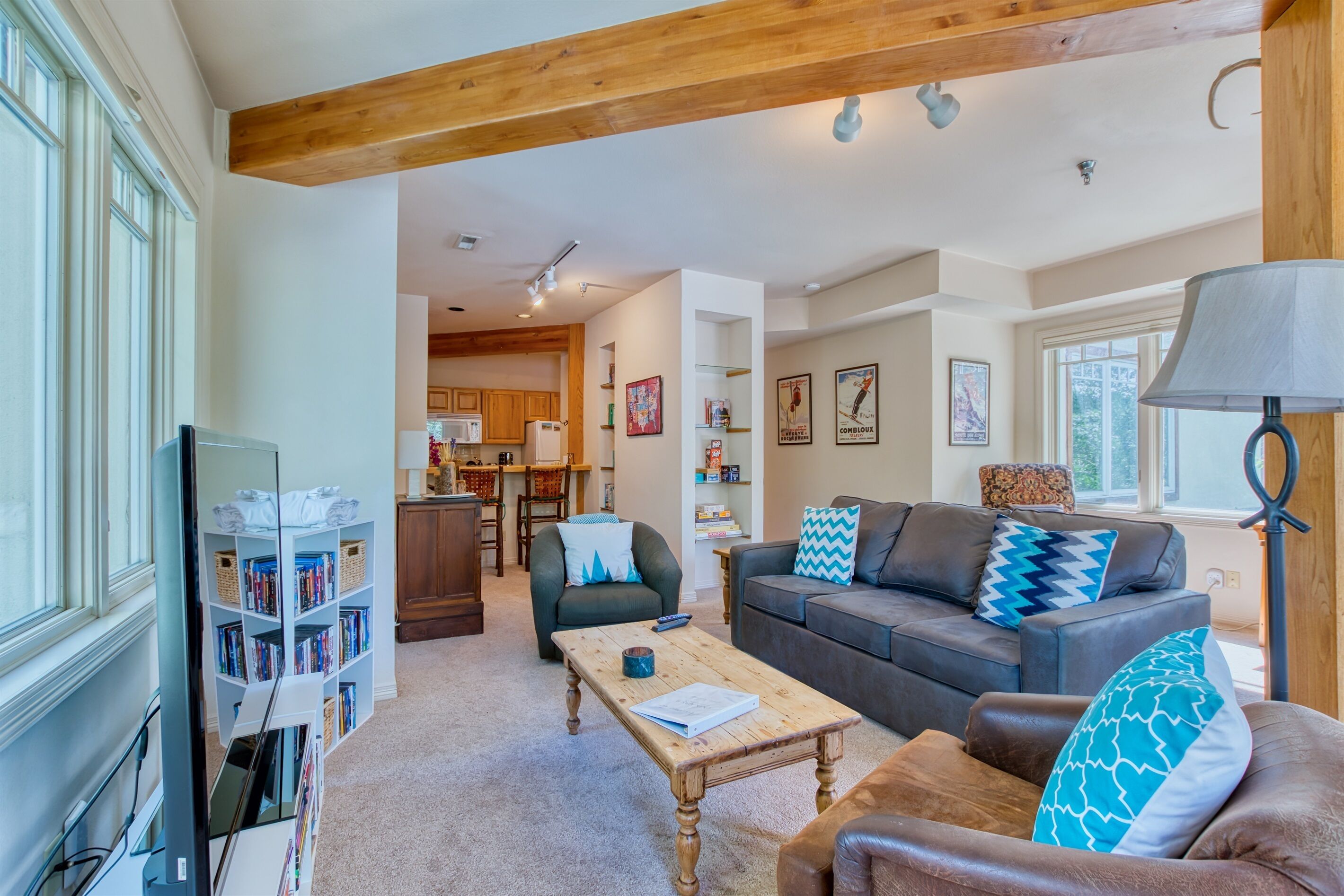 A spacious living room with a wooden coffee table, leather sofa, and a bookshelf.