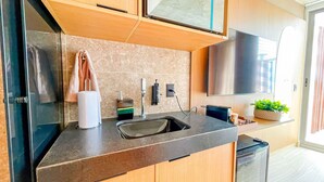 A modern kitchen with a built-in sink, a countertop, and a wall-mounted TV. - Yacht - by Setai Apartaments (João Pessoa)