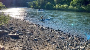 Un río con barcos, una orilla rocosa y un edificio al fondo.