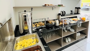 A buffet setup with various food items and kitchen appliances. - Pousada Village (Florianopolis)