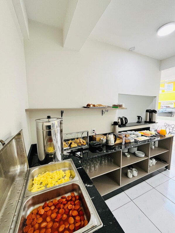 A buffet setup with various food items and kitchen appliances. - Pousada Village (Florianopolis)