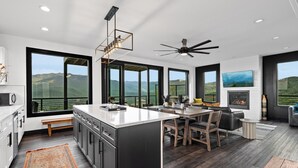 A modern kitchen with a large island, dining area, and a fireplace. - Swim Spa/VIEWS/Hot Tub/Game Room - Viewfinder (Gatlinburg)