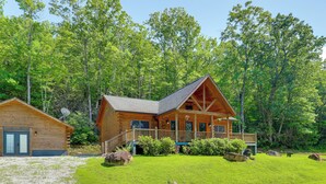 A log cabin with a porch, surrounded by a well-maintained lawn and trees. - Updated Cabin By Linville Falls: Deck & Game Room! (Marion)