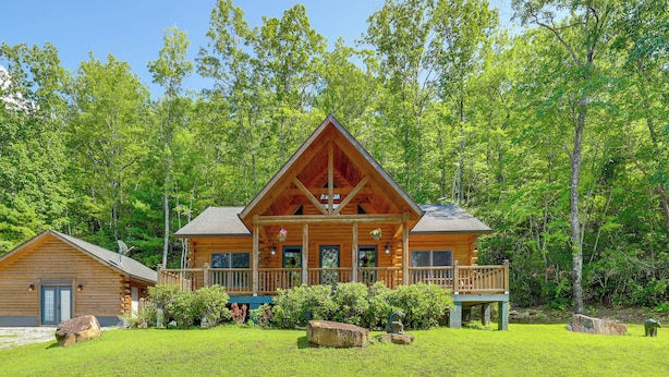 A log cabin with a porch, surrounded by lush greenery and trees. - Updated Cabin By Linville Falls: Deck & Game Room! (Marion)