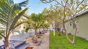 A residential area with a sidewalk, small trees, and a palm plant. - Walk to Dining & Sand! St Pete Beach Apartment (St Pete Beach)
