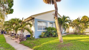 A single-story house with a blue exterior, surrounded by a well-maintained lawn and palm trees. - Walk to Dining & Sand! St Pete Beach Apartment (St Pete Beach)