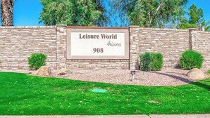 A sign for "Leisure World Arizona 908" with a stone wall and green grass in the foreground. - Leisure World Oasis. Charming 2-bedroom townhome. 24 Hours security in Mesa (Mesa)