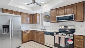 A modern kitchen with wooden cabinets, stainless steel appliances, a dishwasher, and a built-in oven. - Leisure World Oasis. Charming 2-bedroom townhome. 24 Hours security in Mesa (Mesa)