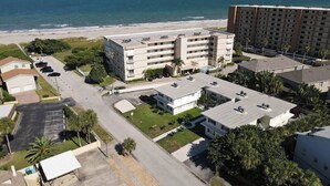 A coastal hotel with multiple buildings, a parking lot, and a beach view.