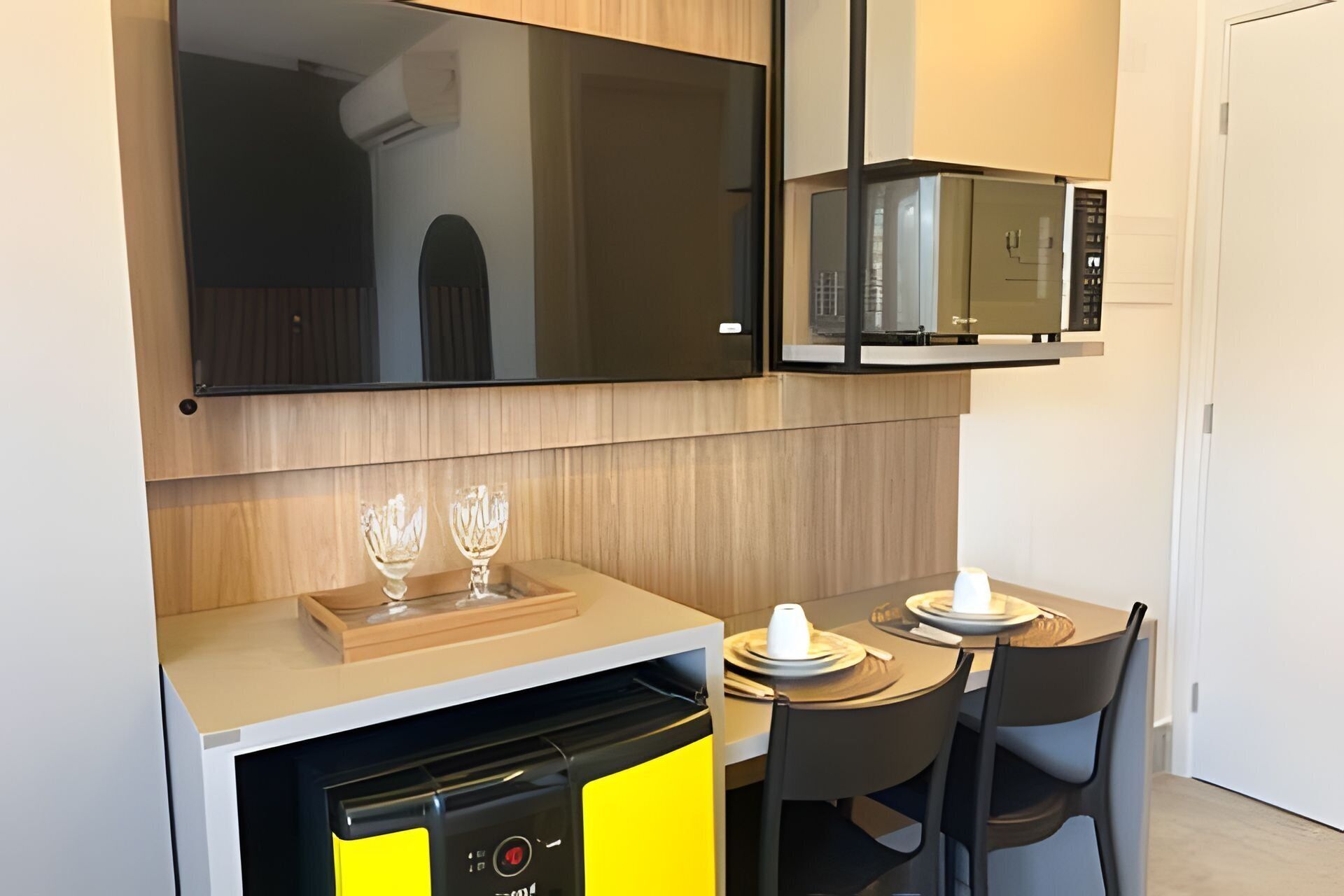 Una kitchenette compacta con microondas, lavavajillas y un pequeño comedor con dos sillas y una mesa.