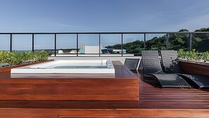 A rooftop terrace with a hot tub, lounge chairs, and a view of the cityscape. - Legacy Suites (João Pessoa)