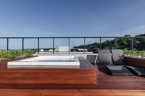 Una terraza en la azotea con un jacuzzi, sillones de descanso y vistas a la ciudad.