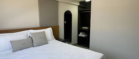 A hotel room with a bed, a wardrobe, and an air conditioning unit.