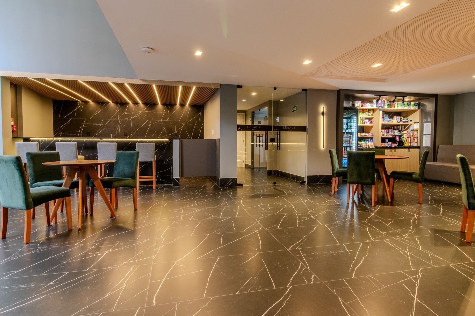 Eine moderne Hotelhalle mit Marmorboden, einer Sitzecke mit Stühlen, einer Bar und einer Rezeption.