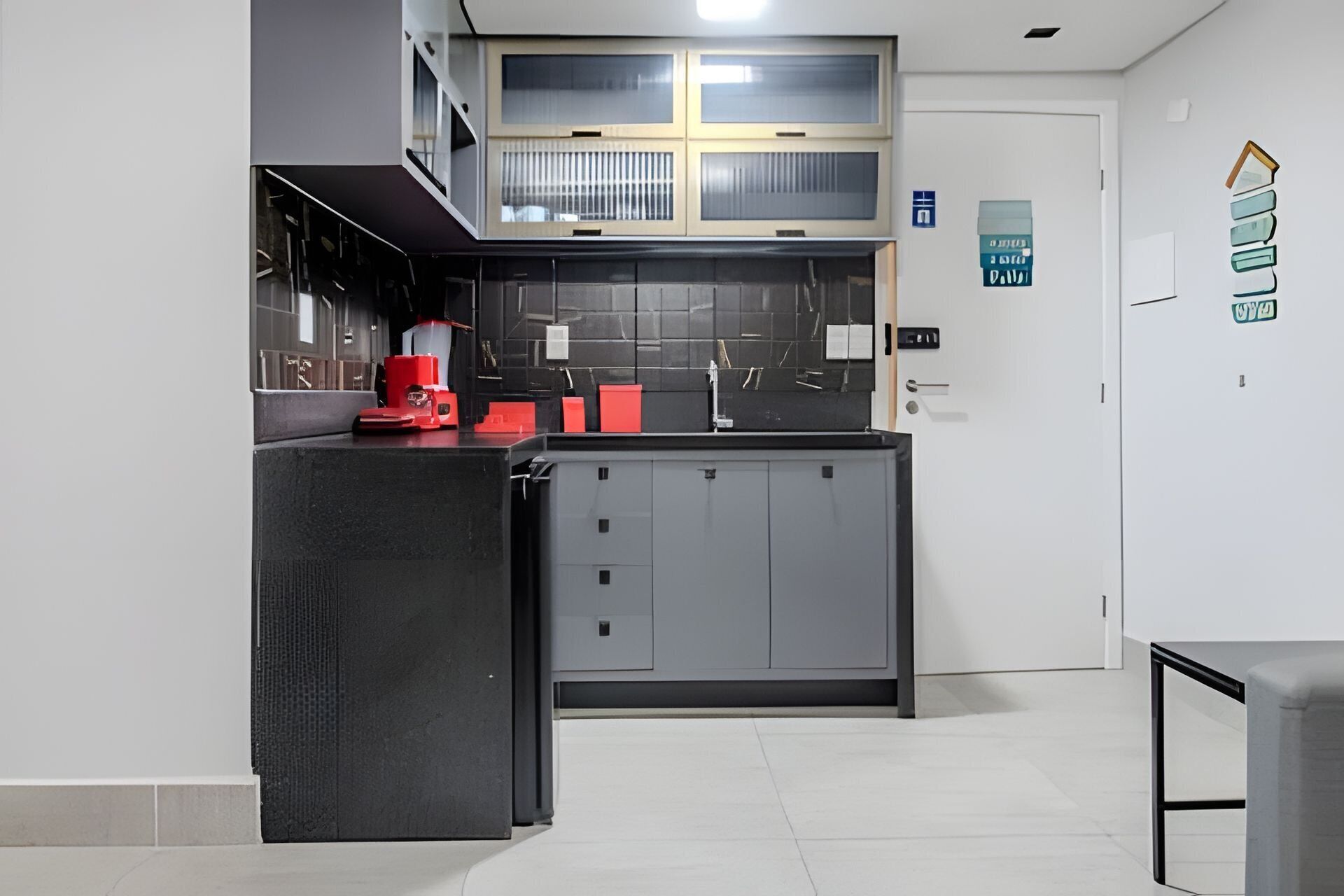 Una cocina moderna con encimera negra, un electrodoméstico rojo y armarios grises.