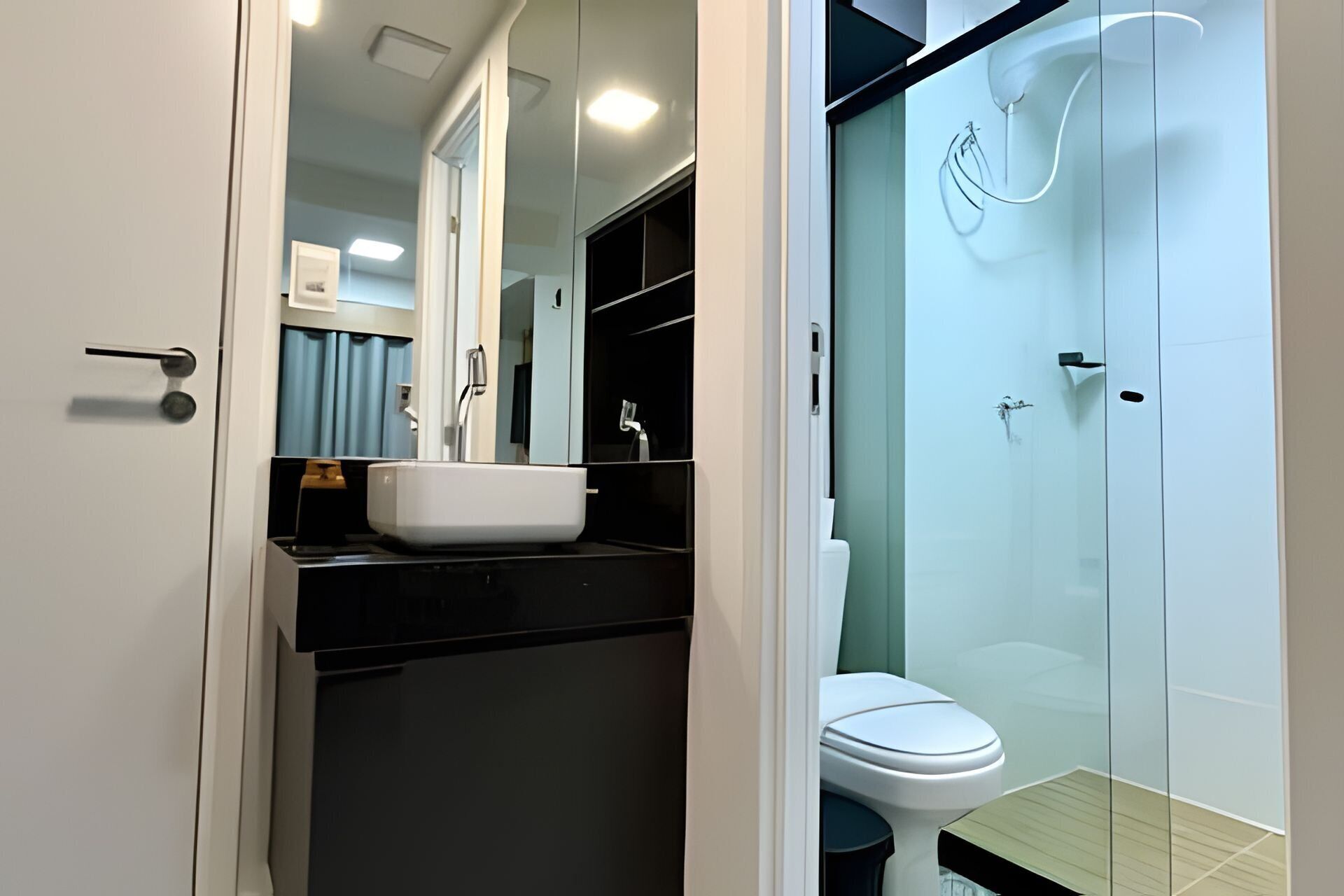 Et moderne badeværelse med en hvid vask, toilet og en brusekabine i glas.