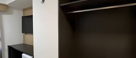Una habitación con escritorio, refrigerador pequeño, televisor montado en la pared y estanterías integradas.