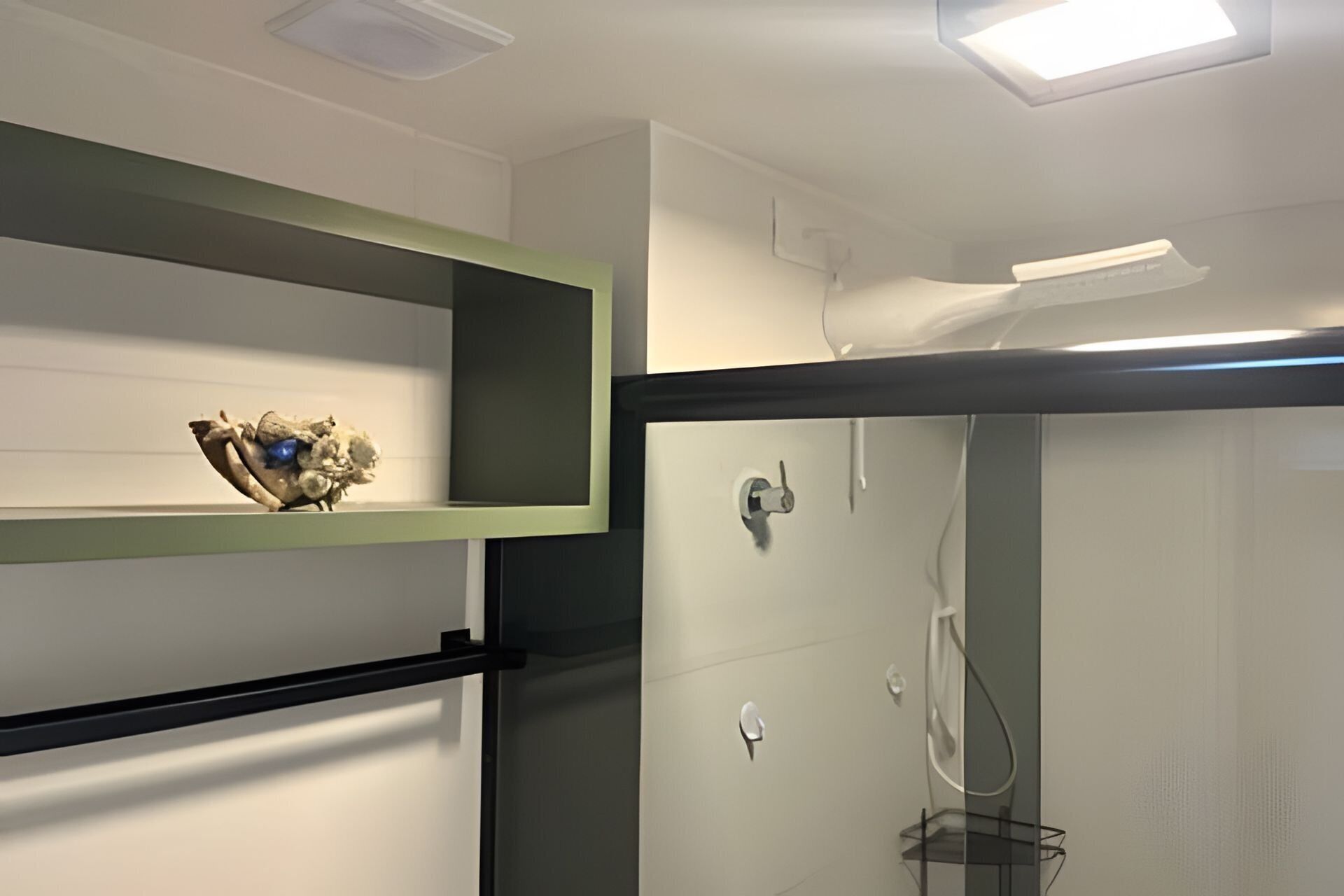 A bathroom with a shower, a shelf with a decorative item, and a towel rack.