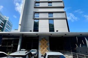 A modern building with multiple floors, large windows, and a parking garage below. - Legacy Suites (João Pessoa)