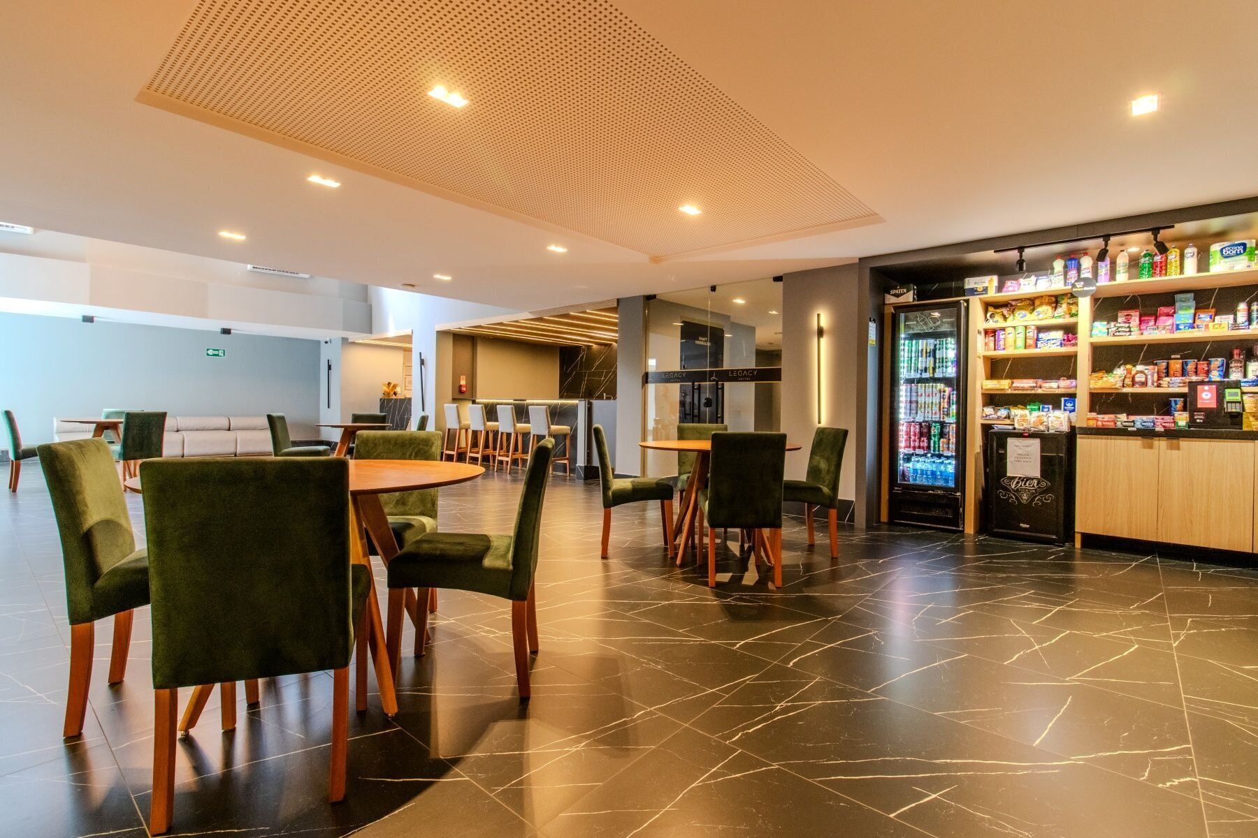 Um lobby de hotel moderno com área de estar, bar e máquina de vendas.