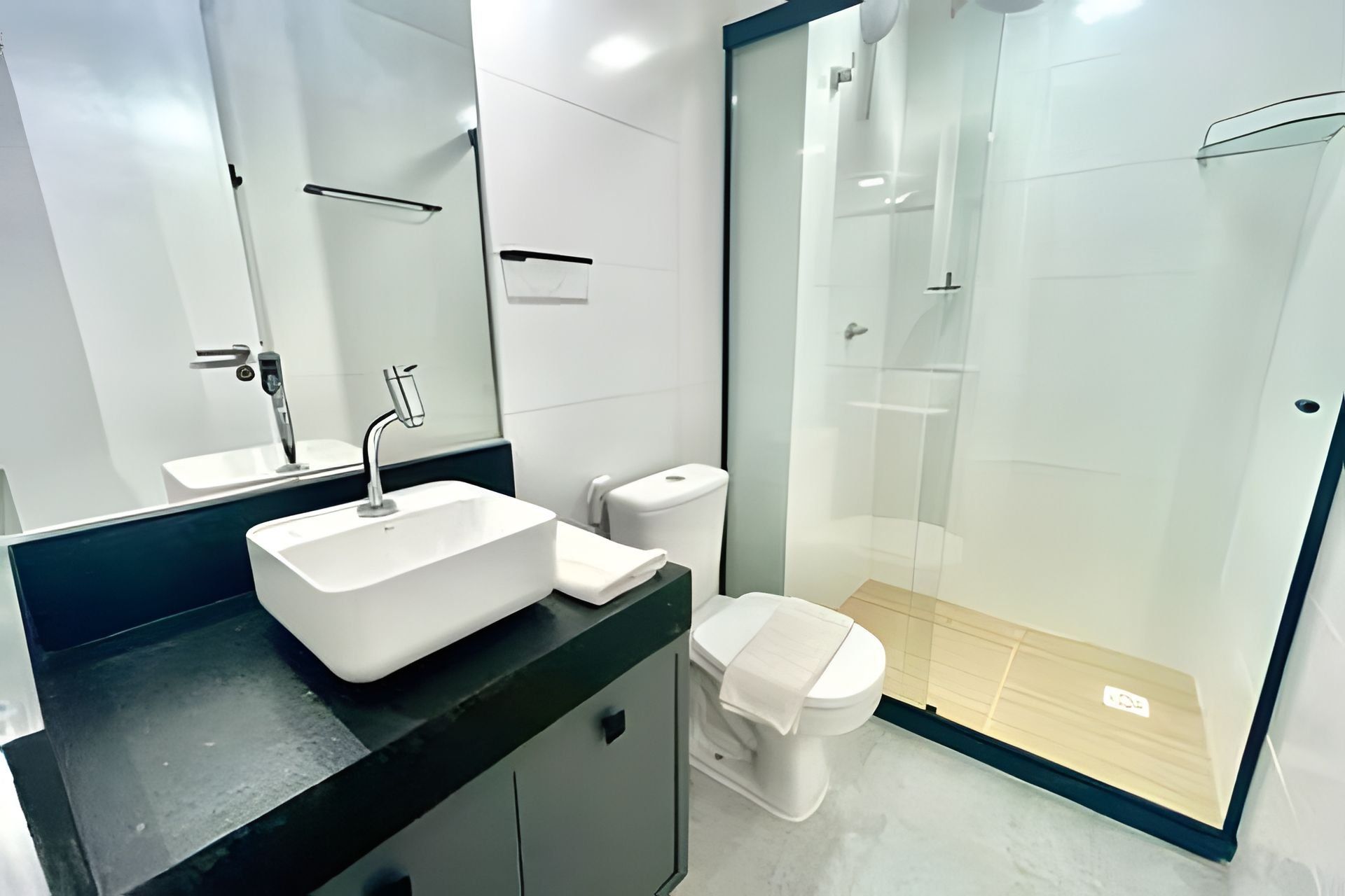 A modern bathroom with a white sink, toilet, and glass-enclosed shower.