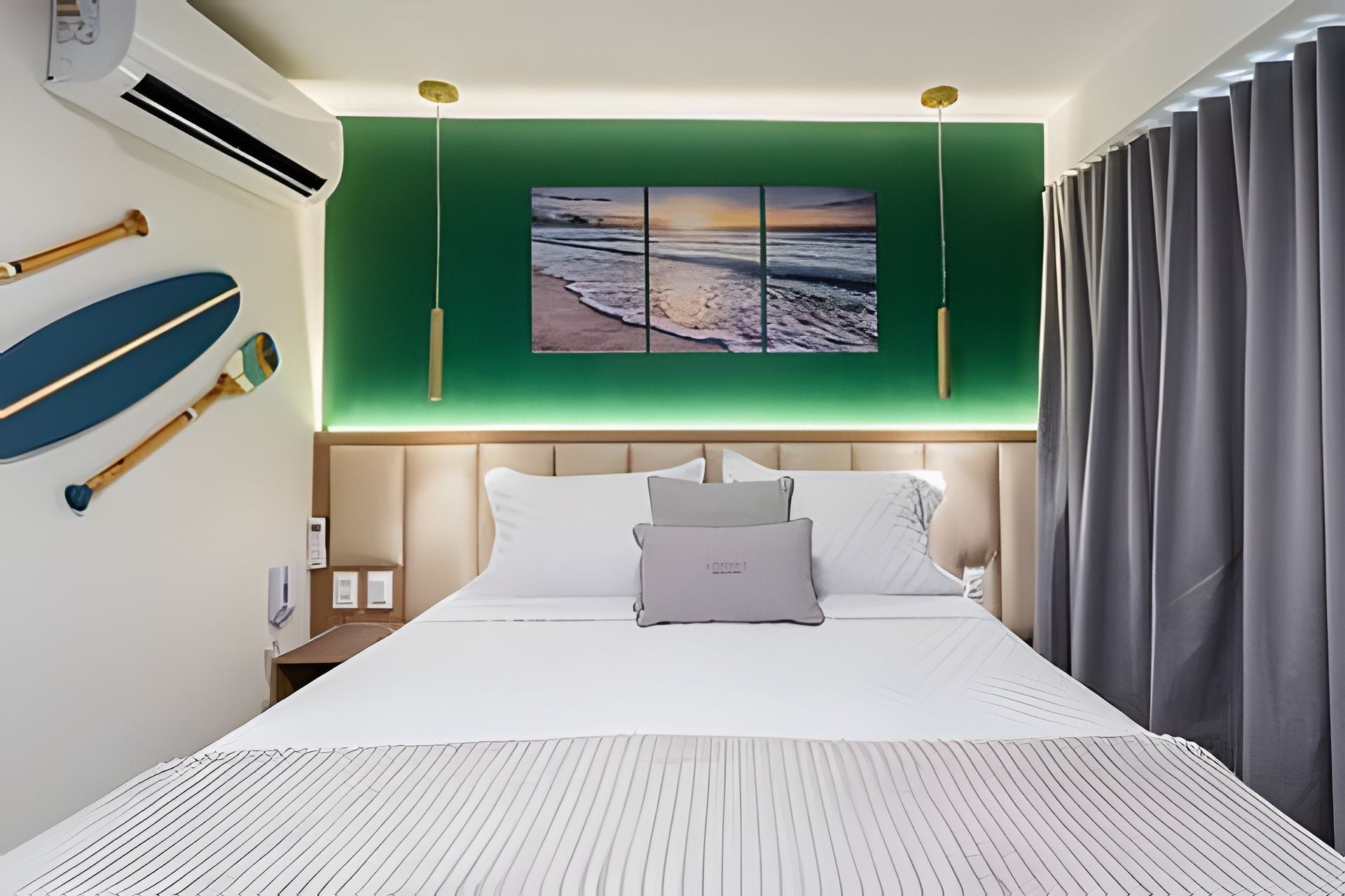 Habitación de hotel con cama, pared verde, un cuadro y una ventana con cortinas.
