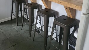 A kitchen with a wooden countertop, four stools, and two jars on the shelf.