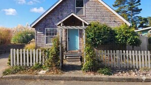 A single-story house with a gabled roof, a front porch, and a picket fence.