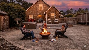 A backyard with a fire pit, outdoor seating, and a house in the background.