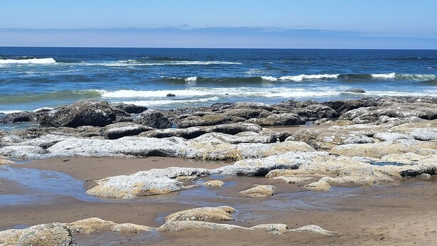 A rocky beach with waves crashing onto the shore.
