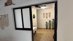 A room with a bed, a ceiling fan, and decorative wall hangings.